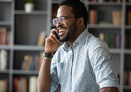 A man smiling while talking on a phone.